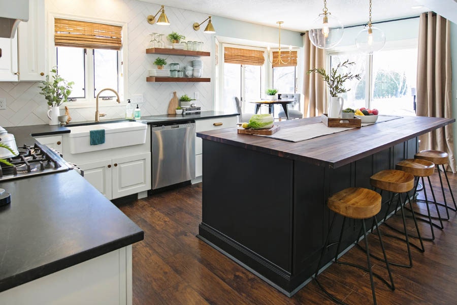 eclectic kitchen with black kitchen island, wood bar stools, and white cabinet perimeter