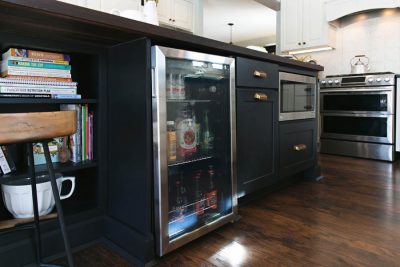 Black kitchen island base with open shelves, a built in microwave, and a built in cooler.