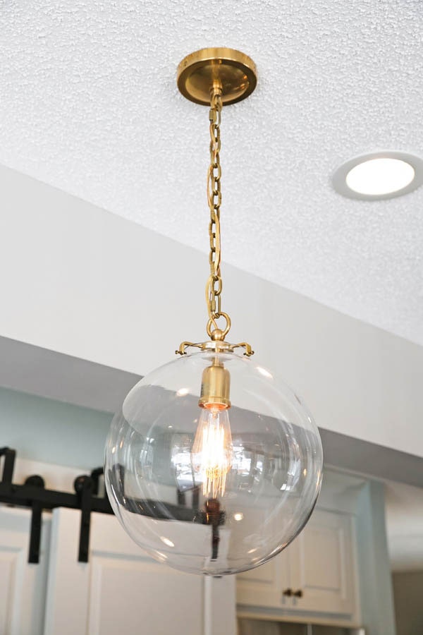 Decorative style kitchen cabinets in white with glass globe pendant with brass hardware