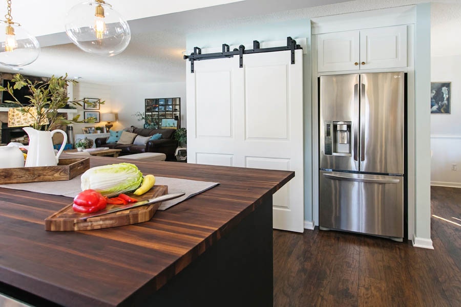 Image of kitchen looking into the living area, and a white barn door.