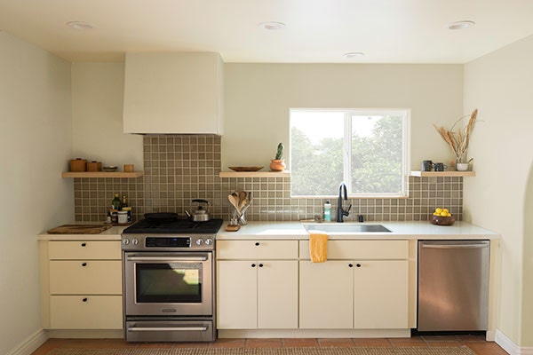 Slab style kitchen in white with tile backsplash and minimalistic wood range hood