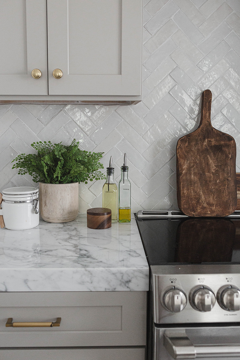 Taupe shaker cabinets with gold hardware and white marble countertops