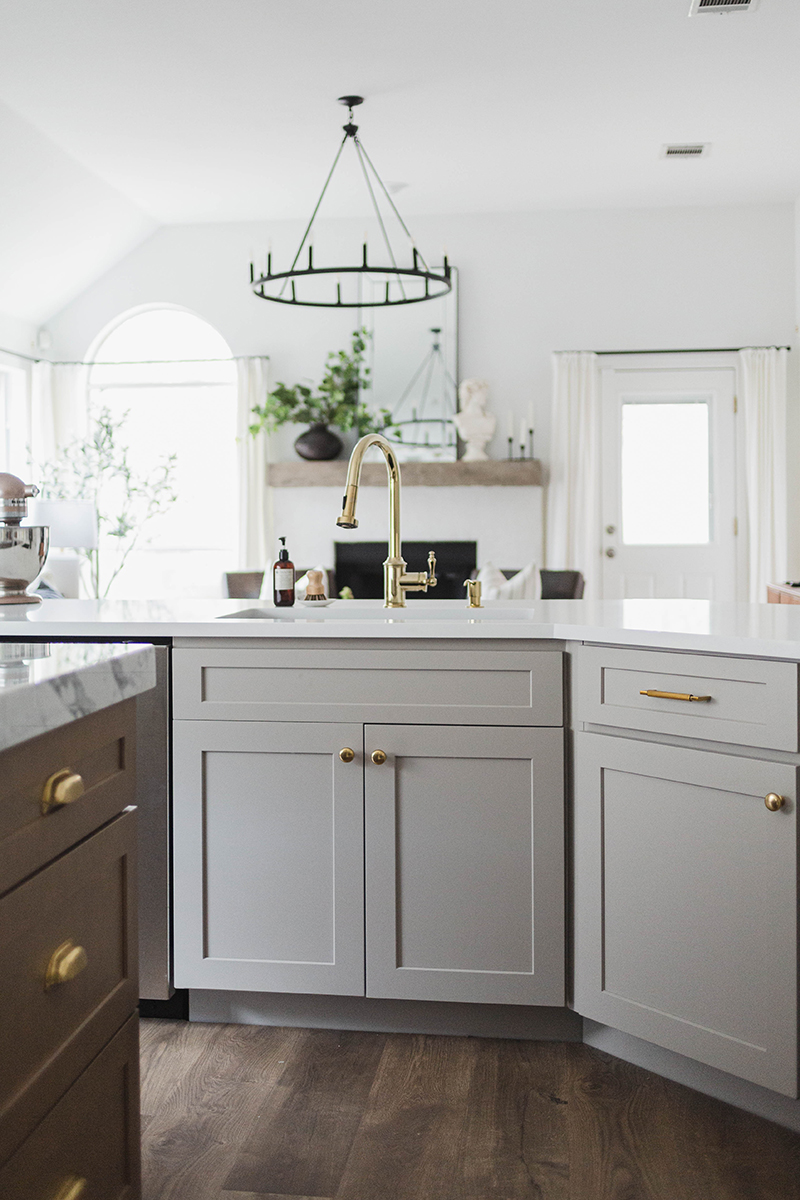 CliqStudios project: Light gray shaker kitchen cabinets and chestnut stained island with marble countertops and white, gold, and black accents