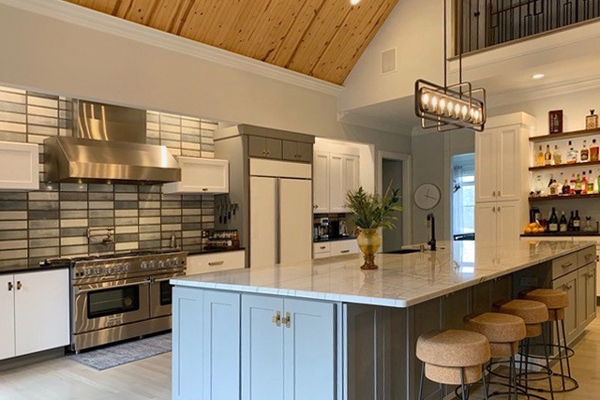 Slab white kitchen cabinets with large shaker gray island and oil rubbed bronze light fixtures