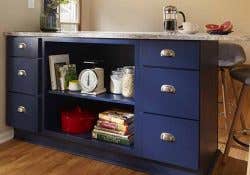 A blue peninsula with open shelving displaying books