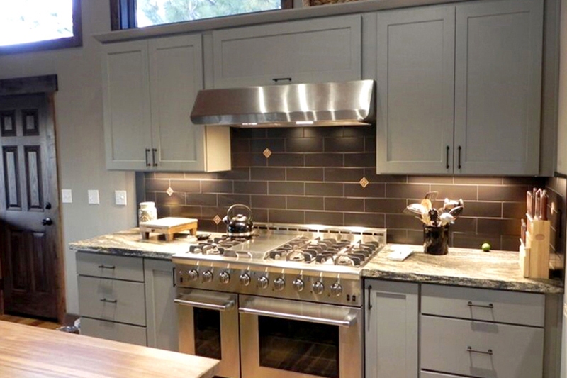 White shaker kitchen cabinets with a stainless steel under mount hood