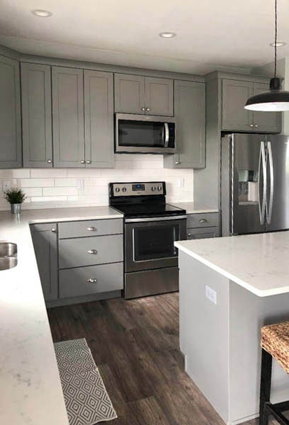 Medium gray kitchen cabinets with subway tile backsplash, stainless appliances and white countertops