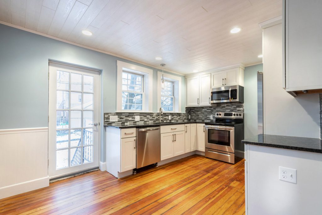 updated kitchen with white cabinets and stainless appliance, with original hardwood floors