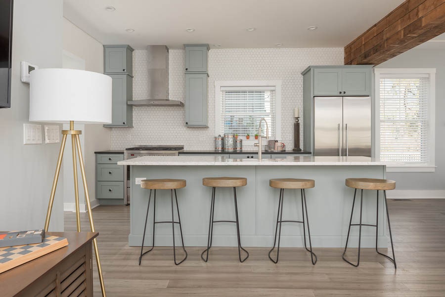 open kitchen with island seating for four with blue-gray cabinets and white backsplash up the wall