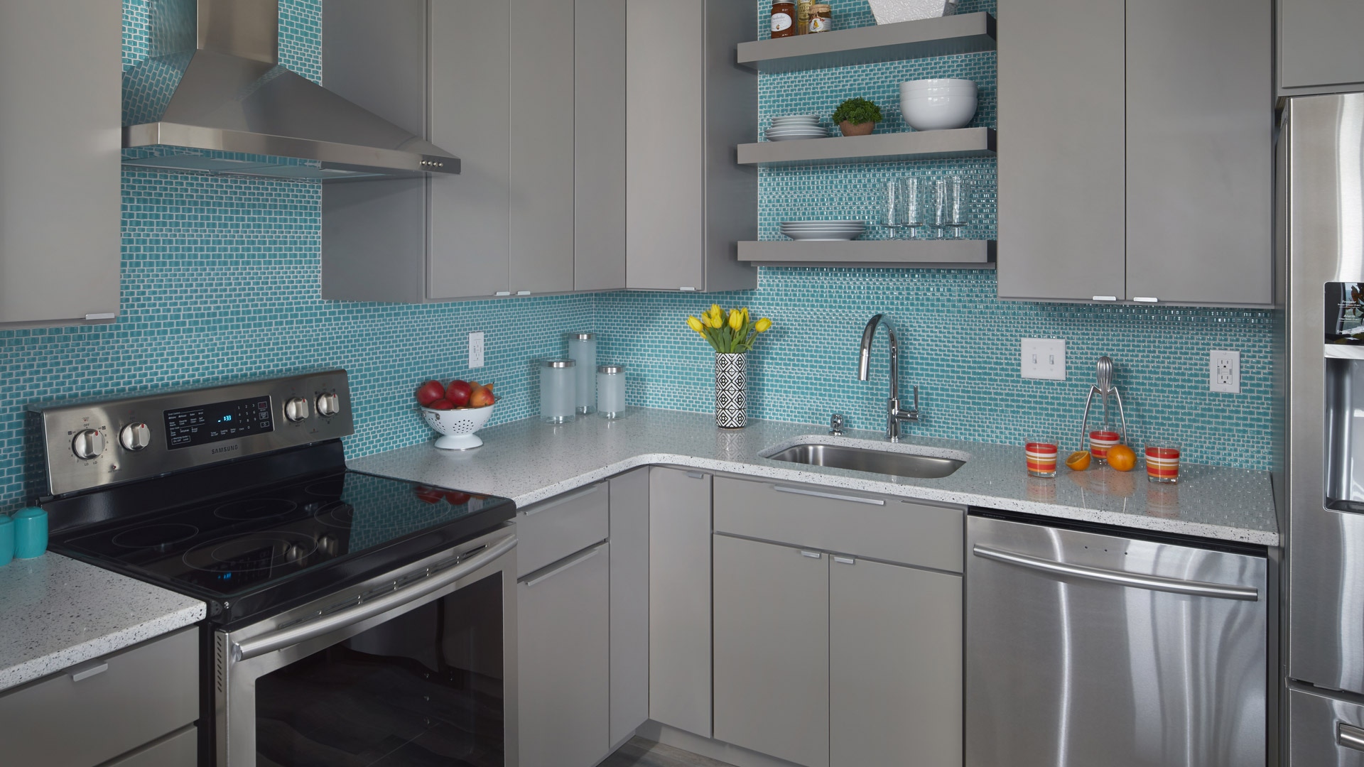 Modern kitchen featuring Gray Slab door style with blue blacksplash and black appliances.