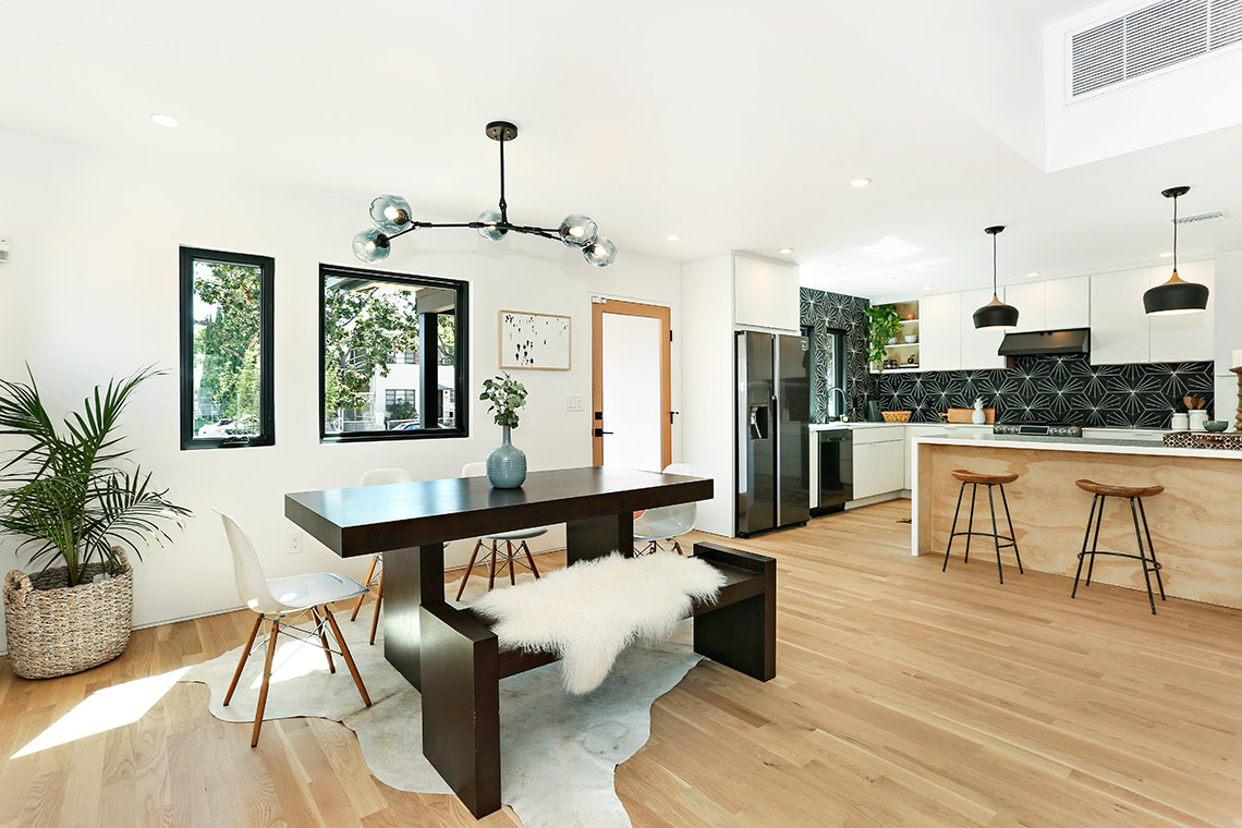 White slab kitchen cabinets with natural wood finish peninsula and black retro backsplash