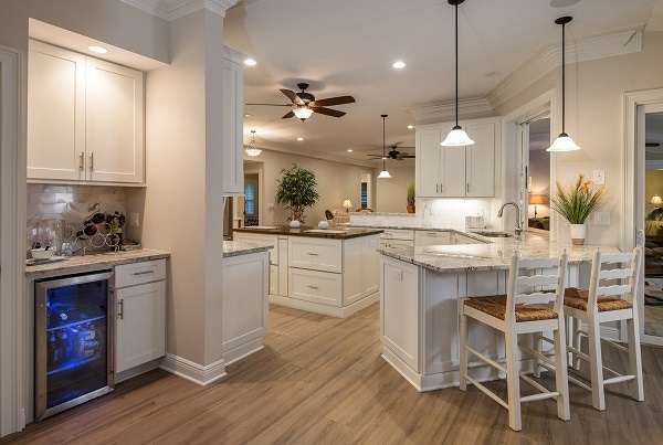 large kitchen has peninsula, center island, open to living and built-in bar using white shaker cabinets