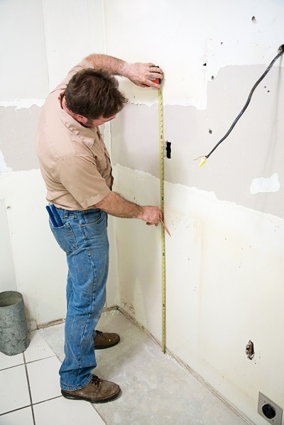 contractor measuring wallboard in kitchen remodel