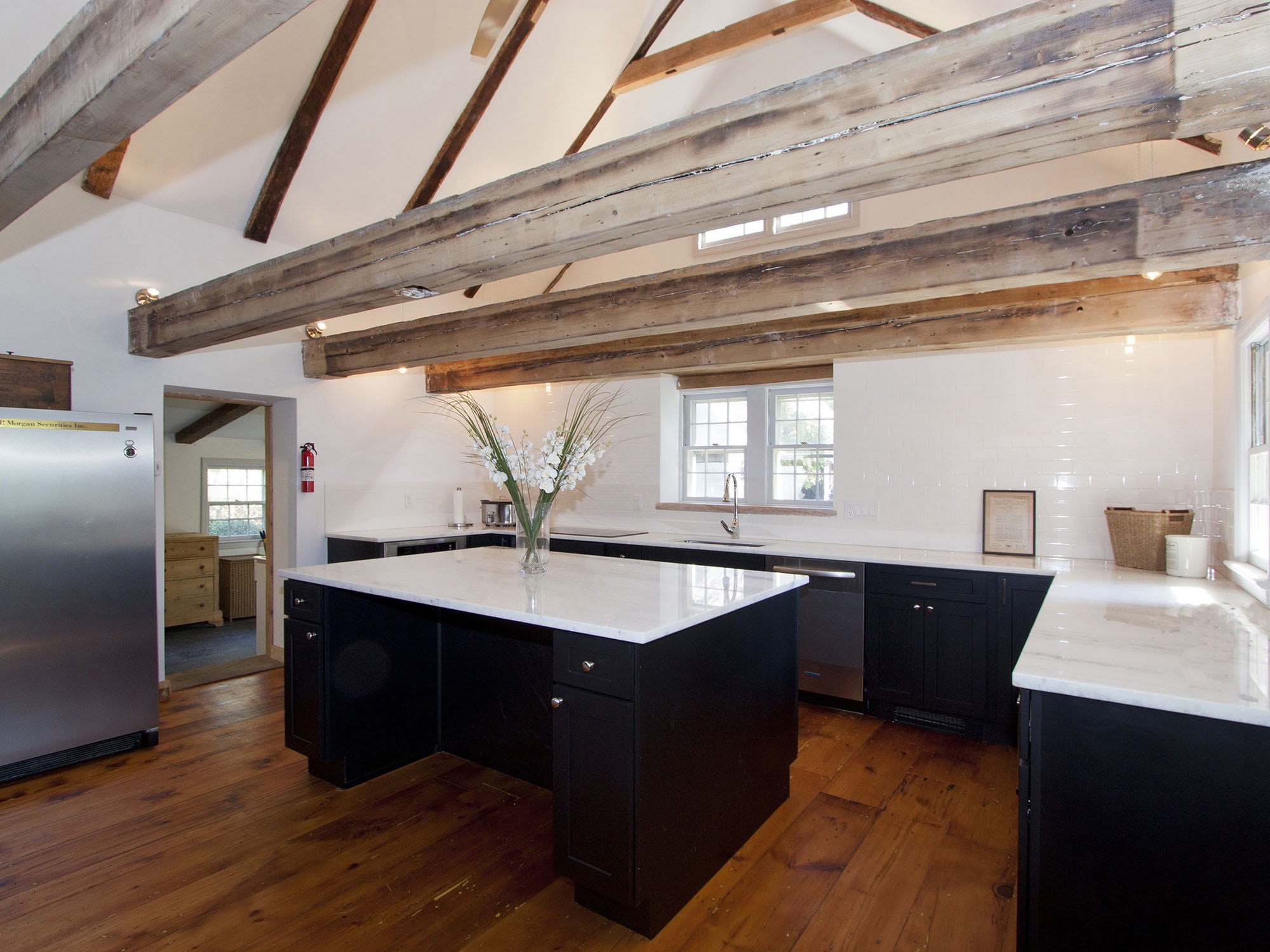 Black shaker base cabinets with white countertops and large wooden ceiling beams