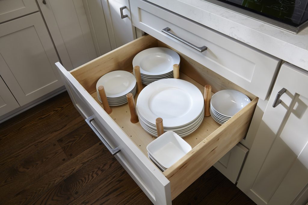 Peg drawer organizer storing plates, dishes, and bowls. Shown in CliqStudios Shaker style, Painted light gray