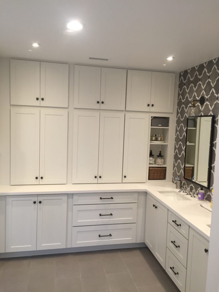 Master bathroom with L-shaped white shaker vanity cabinets, double sinks and lots of pantry storage.