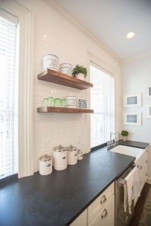 picture of kitchen wall with windows, open shelves, black countertop, farm style sink and shaker cabinets with cup pulls