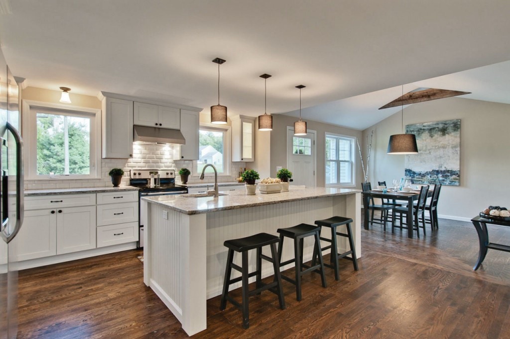 Spacious kitchen has painted white Shaker cabinets, large island with seating and a sink, opens to dining room.