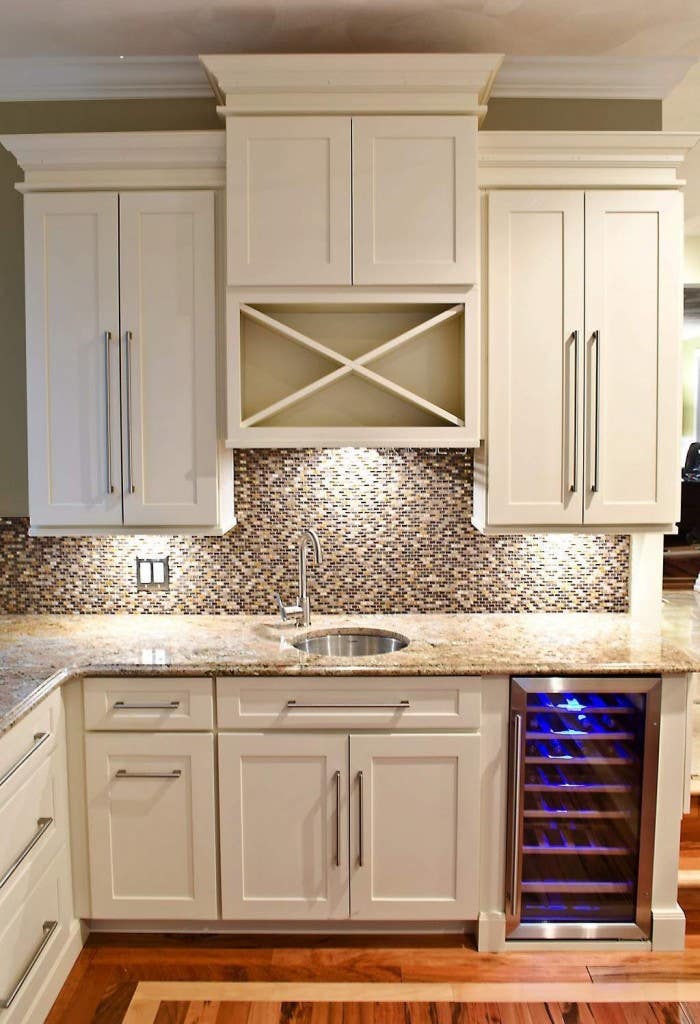 wet bar built of white shaker cabinets with built-in wine cooler in base and wine rack above sink