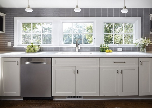 Kitchen window wall with pale gray shaker cabinets and gray subway tile