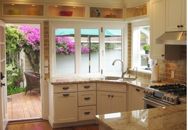 California kitchen with shaker white cabinets has pass-through windows over the sink that open to a patio bar