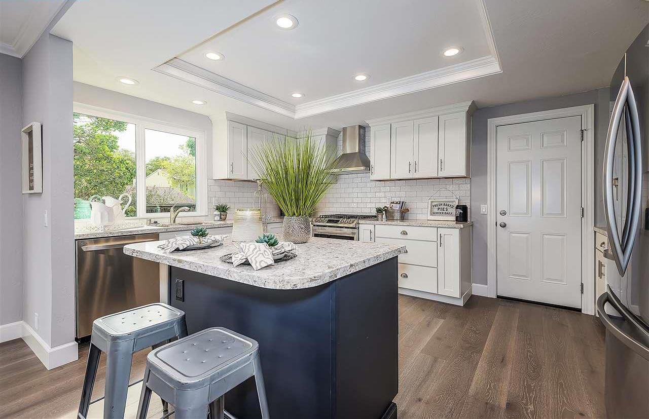 White shaker-style kitchen cabinets with blue shaker island and white quartz countertops