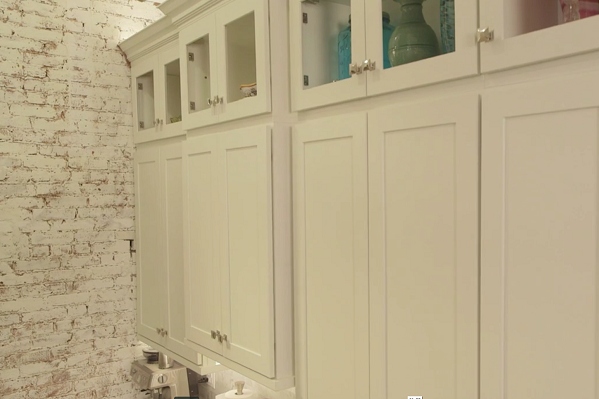 white shaker wall cabinets with upper tier of glass door cabinets, crown molding and over cabinet lighting