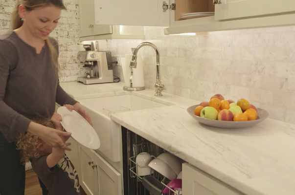 mother and child loading dishwasher