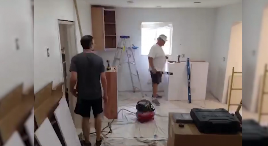 Contractors working in an empty room with tools installing kitchen cabinetry