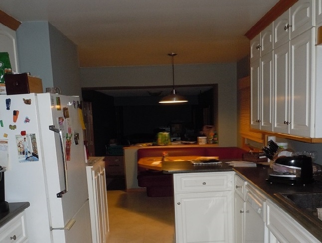 Galley kitchen with white cabinets and breakfast booth ready for remodel