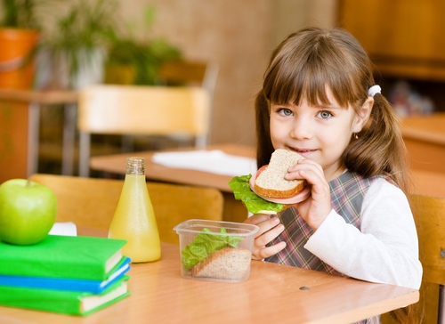 girl with pigtails eating lunch at school desk