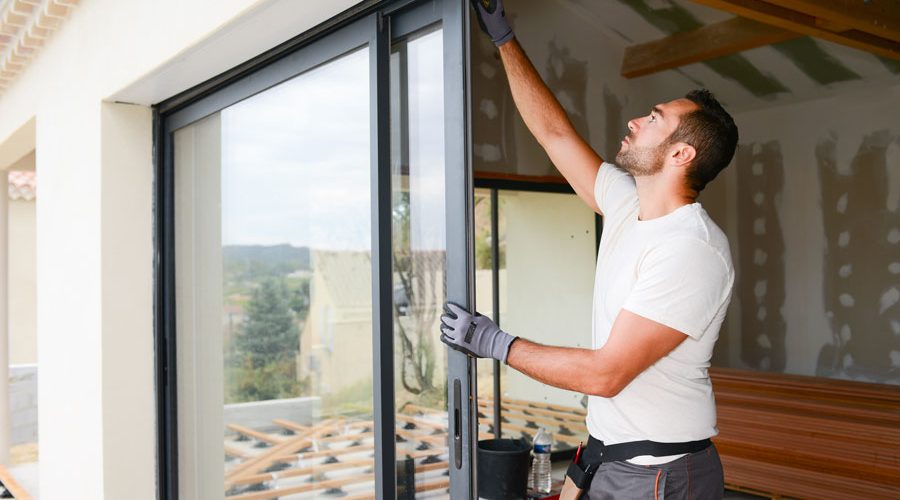 Young window installer in white t-shirt putting in a door while remodeling a house