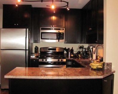 u-shaped kitchen with black cabinets and granite countertop