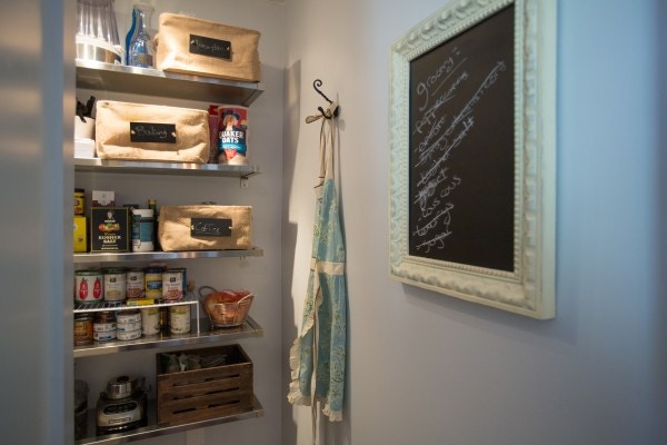 walk-in pantry behind refrigerator has open shelving sotrage