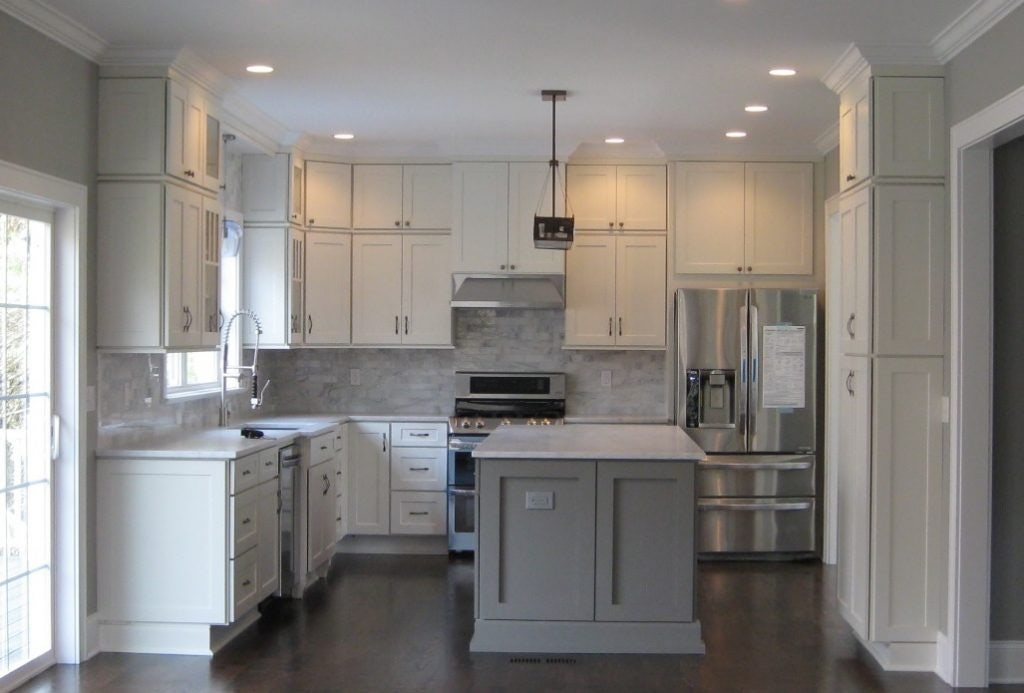 kitchen has white shaker cabinets on the perimeter, gray marble backsplash, soft gray island cabinets and a dark hardwood floor