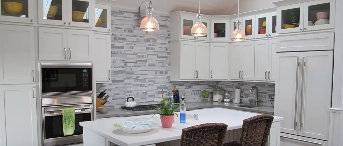  L-shaped kitchen design with a large kitchen island with built-in storage, white shaker cabinetry, and silver cabinet pulls.