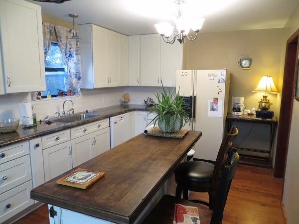 Tennessee kitchen has white shaker cabinets and unique vintage island with solid wood slab counter