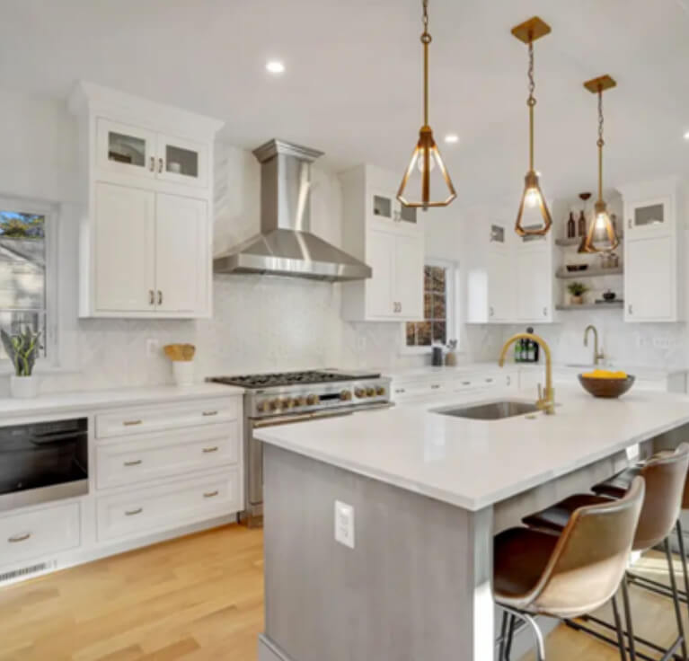 Stacked white inset kitchen cabinets with a large gray island