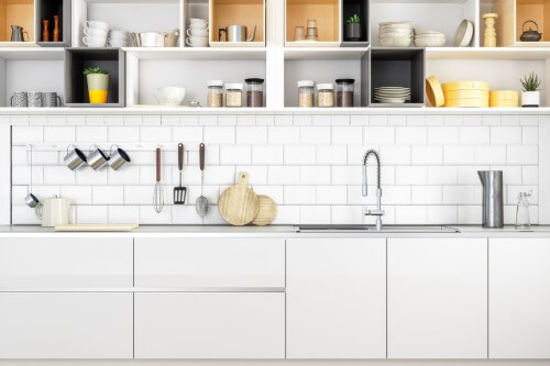 Modern white slab kitchen cabinets with open kitchen cabinet storage above filled with food storage, cups and bowls