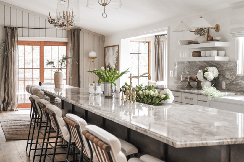 White shaker kitchen base cabinets and white floating shelves with a dark brown stained island and cream and brown granite countertops.