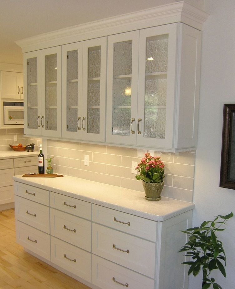 shallow buffet built of white shaker cabinets with textured glass doors and sash pulls