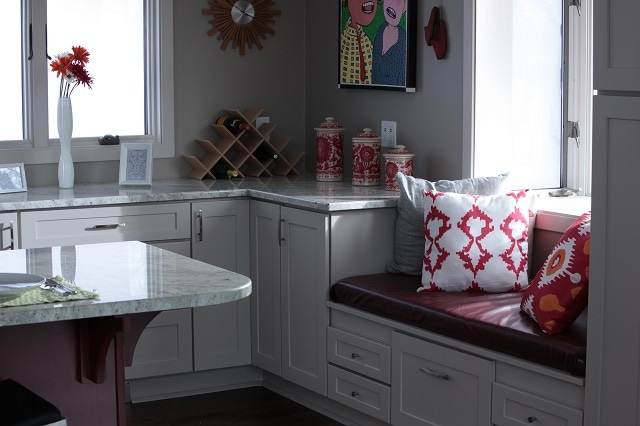 Kitchen window seat built from white cabinets with red cushions