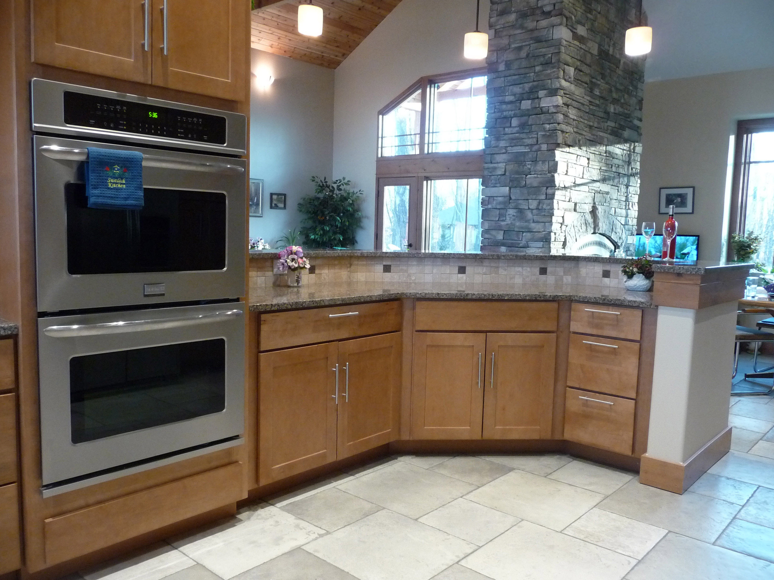 Hex kitchen peninsula in maple shaker cabinets adjacent to double wall ovens