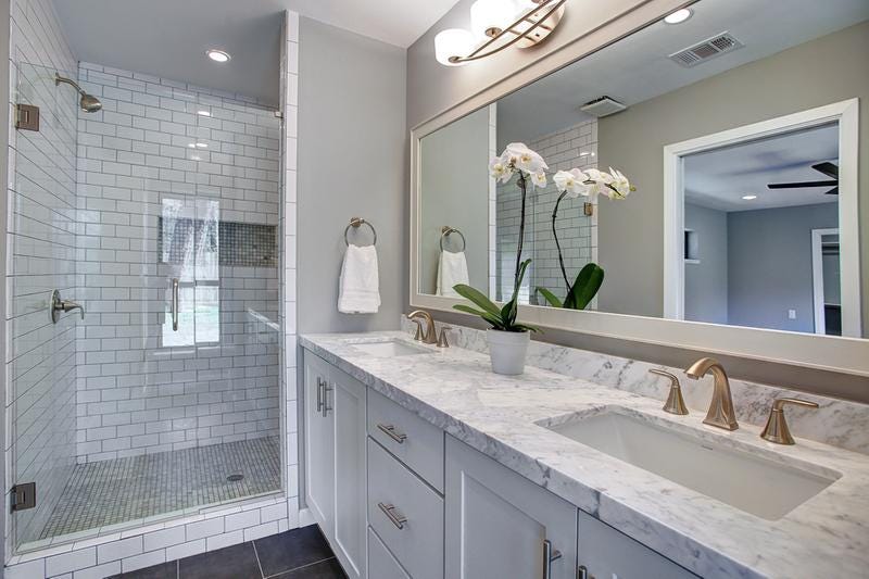 Master bathroom with white shaker vanity cabinets, double sinks and a walk-in tile shower