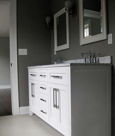 double vanity in bath is built from white shaker cabinets with stainless bar pulls