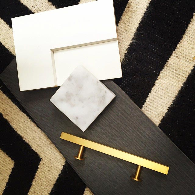 Kitchen sample pieces like cabinet and granite samples on a black and white zig-zag rug.