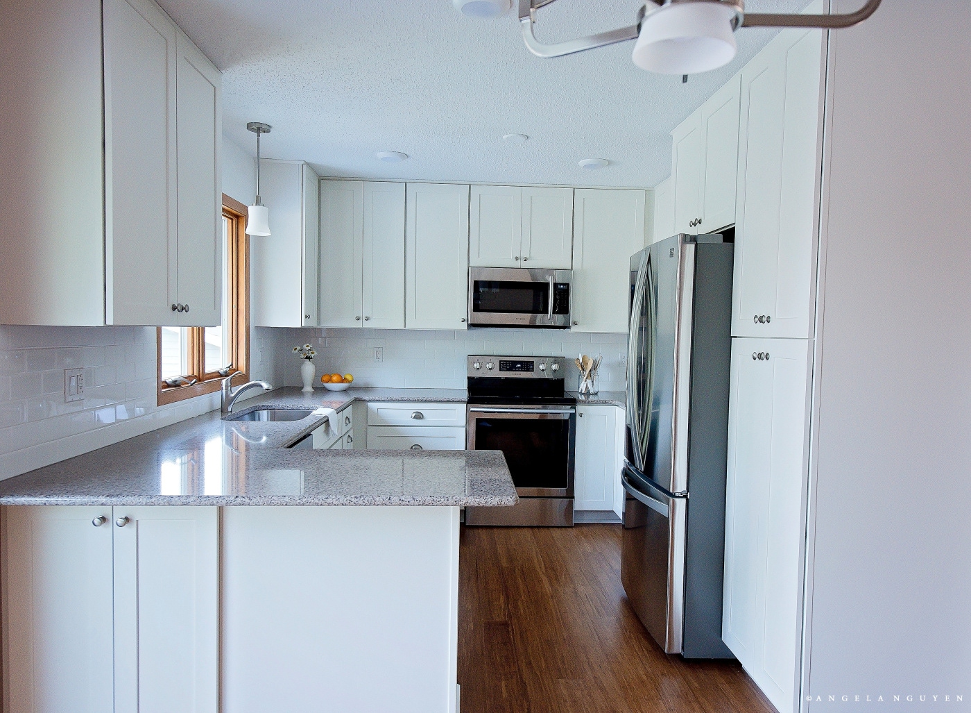 full view of g-shaped kitchen with white shaker cabinets