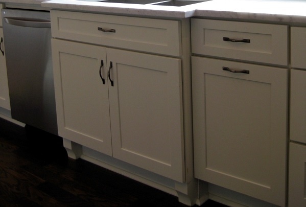 white shaker cabinets in sink area are bumped out with furniture feet