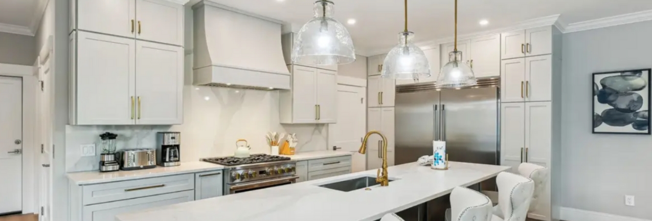 Light gray shaker kitchen cabinets with a dark wood island and gold cabinet hardware